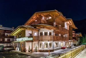 um grande edifício de madeira com uma varanda em Chalet Vites Mountain Hotel em Canazei