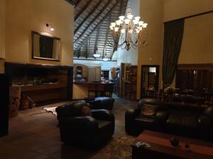 a living room with leather furniture and a chandelier at Tholo Private Game Lodge in Bela-Bela