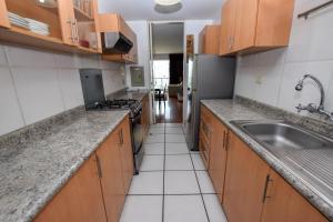 eine Küche mit Holzschränken und einem Waschbecken in der Unterkunft Miraflores4Rent Mar y Vista in Lima