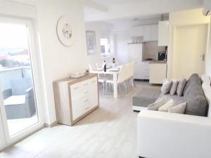 ein weißes Wohnzimmer mit einem Sofa und einer Küche in der Unterkunft Spider Apartments in Pirovac