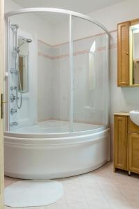 La salle de bains blanche est pourvue d'une douche et d'une baignoire. dans l'établissement Lovely House in the Dolomites, à Mazzin