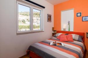 Un dormitorio con paredes de color naranja y una cama con un libro. en Apartment NikoL, en Dubrovnik