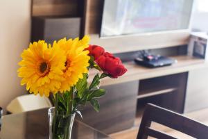 wazon wypełniony żółtymi i czerwonymi kwiatami na stole w obiekcie Miraflores4Rent Upper Pardo w mieście Lima