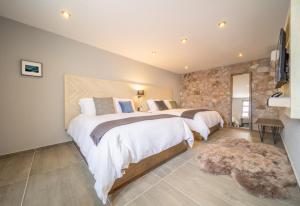 a bedroom with two beds and a stone wall at Hotel Casa Once in Querétaro