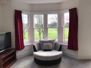 a living room with a chair and a television at Park View - Two bedroom apartment in Worthing