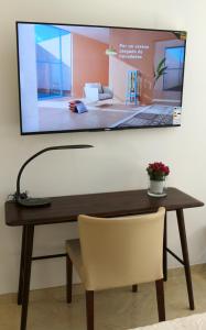 a television hanging on a wall above a table with a chair at Valencia Town Center New Apartments in Valencia