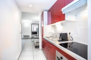 uma cozinha com armários vermelhos e um balcão branco em 202 - Appartement Duplex Moderne - Jeanne d'Arc, Toulouse em Toulouse