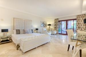 um quarto branco com uma cama grande e cadeiras em Bahía Beach Apartments Estepona em Estepona