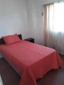 a bedroom with a red bed with a window at Hostal Alessandri in Curicó