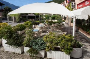 ein Freiluftrestaurant mit Tischen, Stühlen und einem Sonnenschirm in der Unterkunft Hotel Del Mera in Sorico