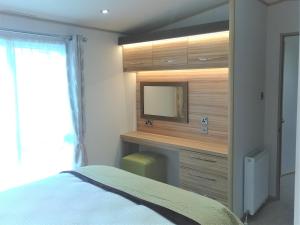 Un dormitorio con un tocador con TV. en Honeydukes Holiday Lodge, Boat of Garten, Aviemore, en Boat of Garten