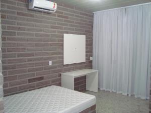 a bedroom with a brick wall with a bed and a mirror at Residencial Infinito - Praia de Palmas in Governador Celso Ramos