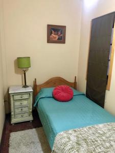 Un dormitorio con una cama con una almohada roja. en Casa porteña en cerro Artilleria, en Valparaíso