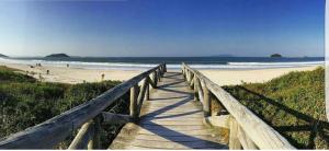 a wooden boardwalk leading to a beach with the ocean at Residencial Infinito - Praia de Palmas in Governador Celso Ramos