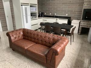 a brown leather couch in a living room with a table at Residencial Infinito - Praia de Palmas in Governador Celso Ramos