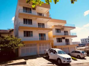 a white suv parked in front of a building at Aconchegante apartamento a beira mar barra velha in Barra Velha