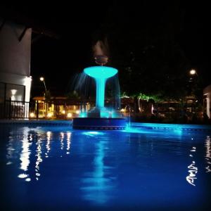 a fountain with blue lights in a pool at night at Rancho Grande Hotel in Villa General Belgrano