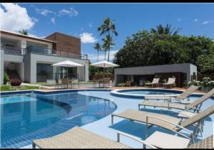 a swimming pool with chairs and a house at Condomínio Solaris Imbassai in Imbassai