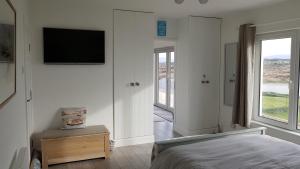 1 dormitorio con 1 cama y TV en la pared en Tidal View, en Kincasslagh