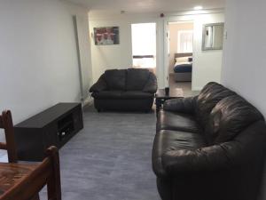 een woonkamer met een leren bank en een tafel bij Sama's Stylish Room 2 in Manchester