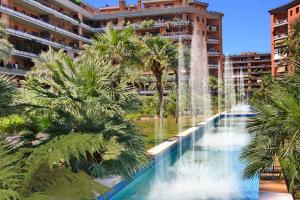 a fountain in front of a building with palm trees at La Fiera GuestHouse in Fiumicino