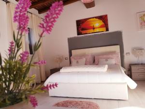 アルデーアにあるL'oasi di Ambraの白いベッドと壁に絵画が飾られたベッドルーム1室