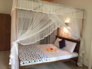 a bed with a canopy with two stuffed animals on it at Ramya Villa in Unawatuna