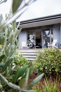 une maison avec deux chaises blanches dans une cour dans l'établissement Polperro Villas, à Red Hill