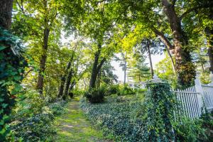 a garden with a white fence and trees at Niagara Mansion Carriage Suite in Lewiston