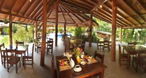 ein Restaurant mit Holztischen und -stühlen und einem Tisch mit Speisen in der Unterkunft Hotel Suizo Loco Lodge & Resort in Cahuita