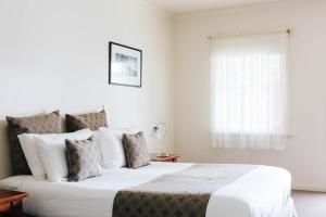 a white bedroom with a large bed and a window at Dunkeld Studio Accommodation in Dunkeld