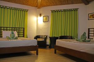 two beds in a room with green curtains at Coron Hilltop View Resort in Coron
