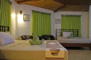 a hotel room with two beds and green curtains at Coron Hilltop View Resort in Coron