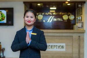 M Hotel Thamel-Kathmandu في كاتماندو: امرأة تقف أمام كونتر بيديها