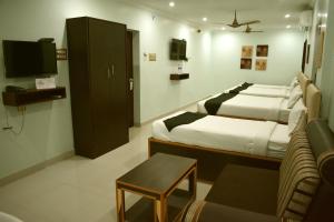 a bedroom with a bed and a tv and a couch at Hotel Apple Park Inn in Tiruchirappalli