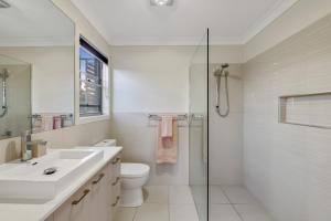 a bathroom with a toilet and a sink and a shower at Fairway Village @ Windaroo Lakes Golf Club in Windaroo