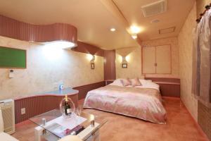 een slaapkamer met een groot bed en een tafel bij Restay Mito (Adult Only) in Mito