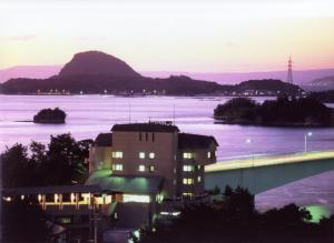 a building in front of a large body of water at Hotel Shosenkaku Romankan in Kami Amakusa
