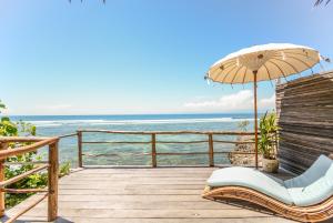 une terrasse avec un parasol, une chaise et l'océan dans l'établissement Le Cliff Bali, à Uluwatu