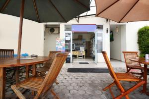 a patio with tables and chairs and an umbrella at Polamas Residence Padang in Padang