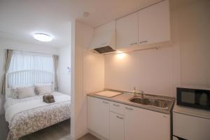 a small kitchen with a sink and a bed at CASA Higashi Mikuni 02 in Osaka