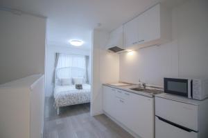 a small kitchen with a microwave and a bed at CASA Higashi Mikuni 02 in Osaka +24 photos