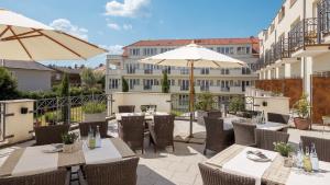un patio con mesas, sillas y sombrillas en Hotel Villa Medici, en Bad Schonborn