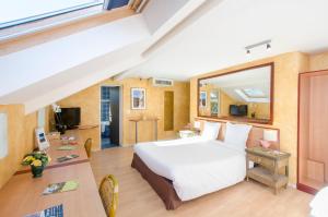 - une chambre avec un grand lit blanc et un bureau dans l'établissement Hôtel Bosquet Pau Centre, à Pau