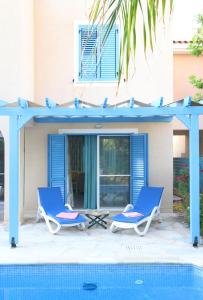- une paire de chaises bleues à côté de la piscine dans l'établissement Polis Beach Village, à Pólis Chrysochoús