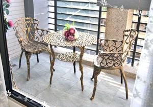 two chairs and a table with a flower on a balcony at Forest Deer Black Tea Homestay in Tainan