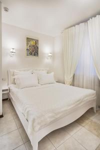 - un lit blanc dans une chambre avec fenêtre dans l'établissement Apart Hotel Quartet, à Odessa
