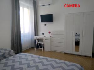 a bedroom with a bed and a desk and a tv at B&B Gaslini & Mare (anche con uso cucina) in Genova