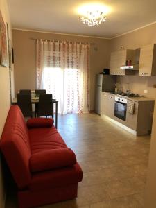 a living room with a red couch and a kitchen at A Casa di Siria in Gela