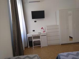 a bedroom with a desk with a television on the wall at B&B Gaslini & Mare (anche con uso cucina) in Genova
